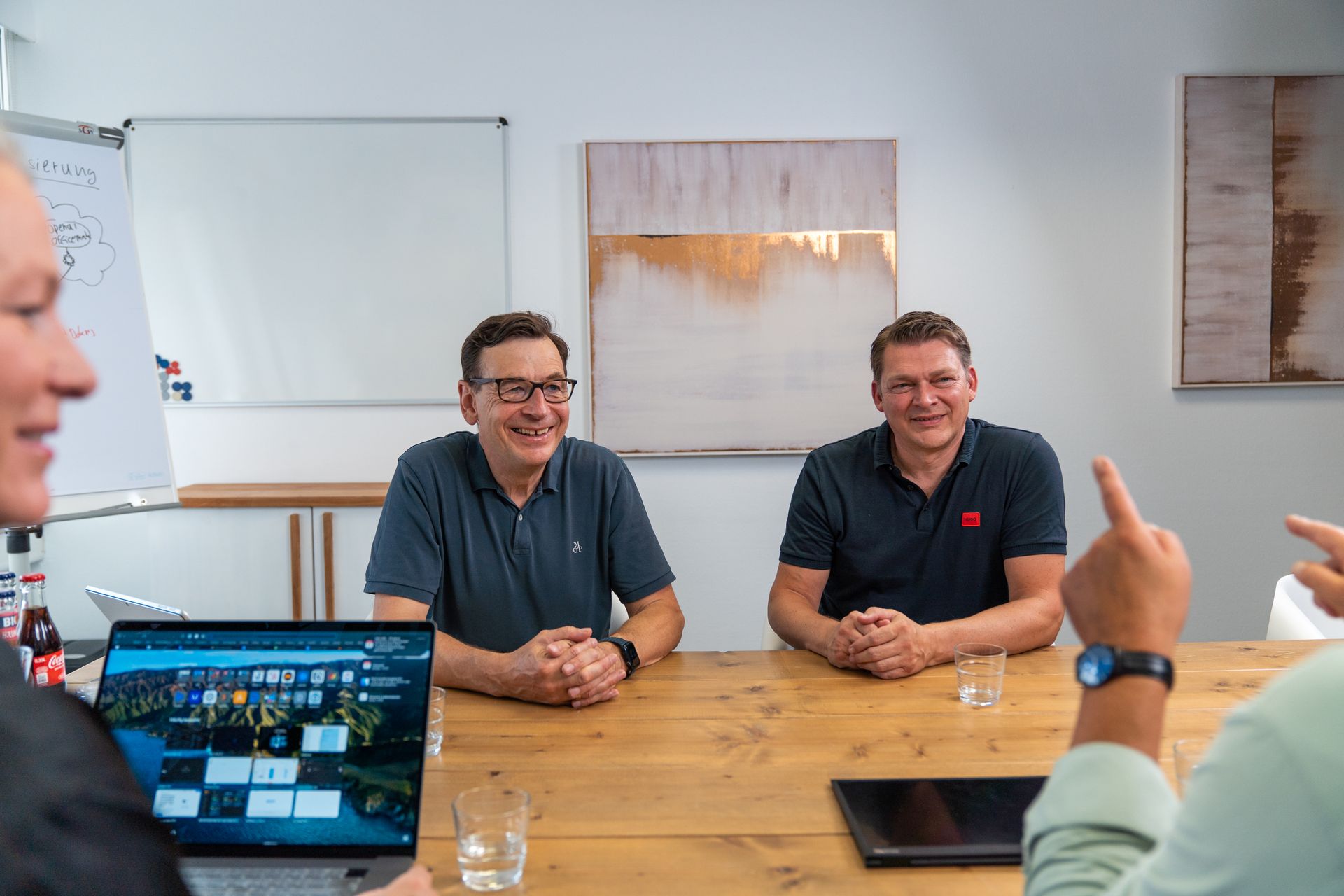 Gespräch am Besprechungstisch mit aufgeklapptem Notebook