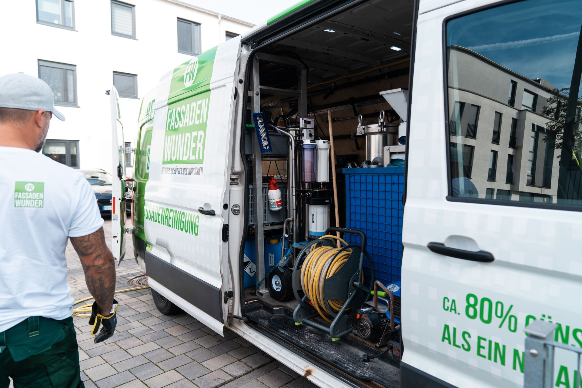Mitarbeiter von Fassaden Wunder am offenen Firmenbus mit Reinigungstechnik und Schlauchtrommel.